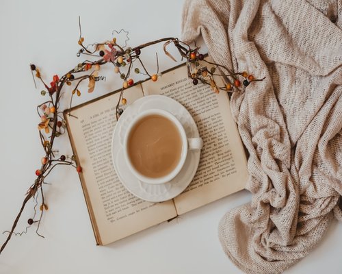A cup of herbal tea next to an open book