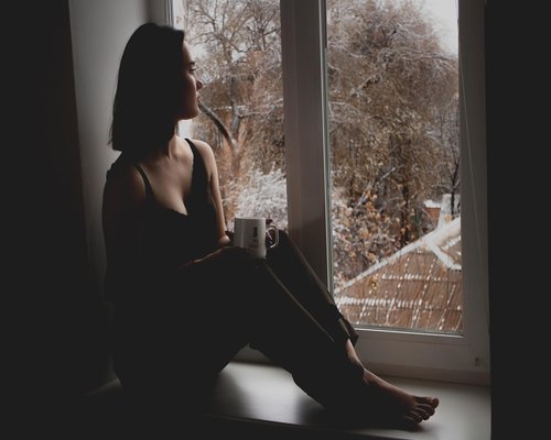 Woman looking out of a window thoughtfully